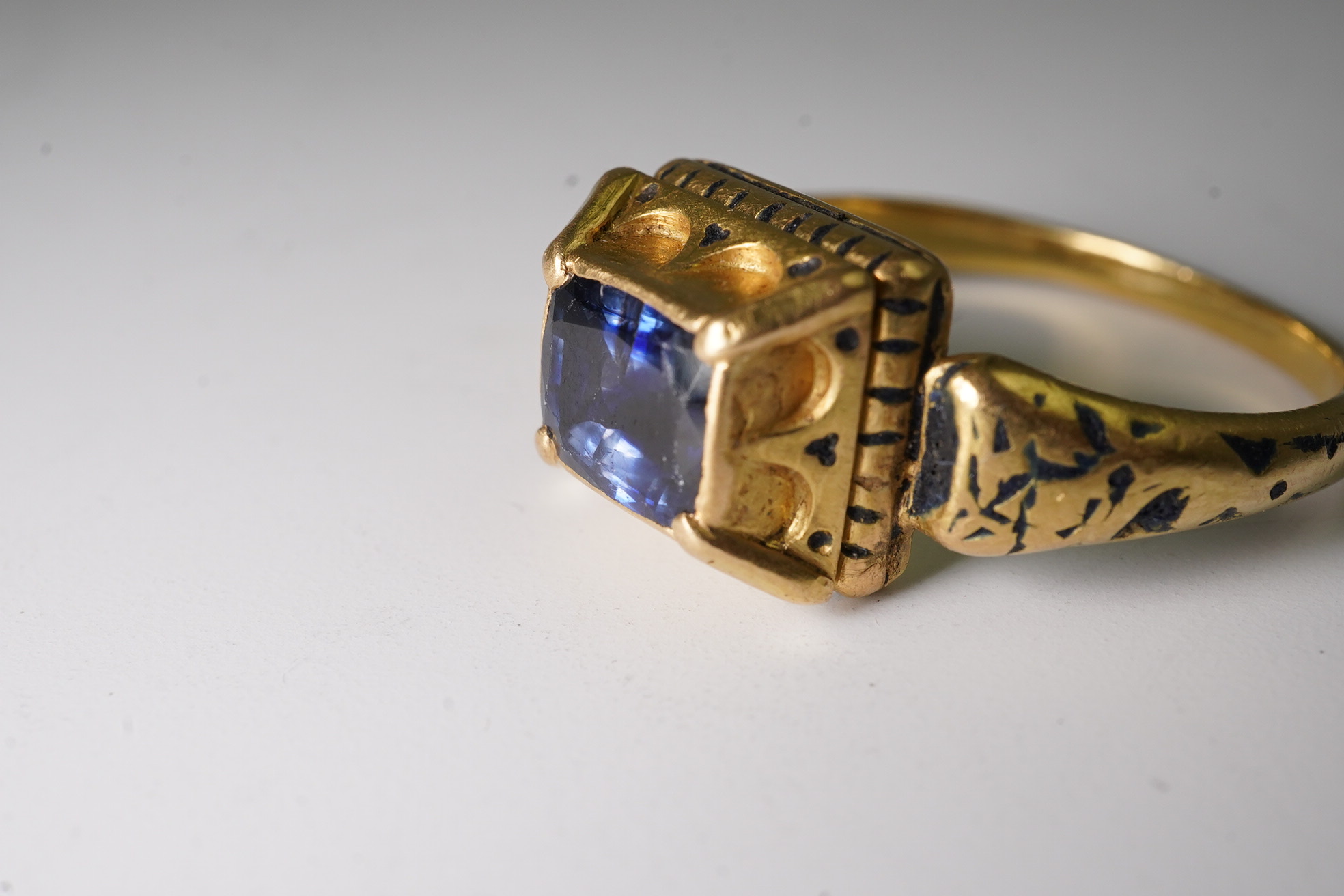 An antique high carat gold, black enamel and collet set cushion cut sapphire set 'poison' ring